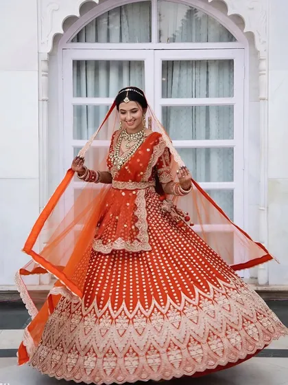 A full-length shot of the bride twirling in her stunning red and white lehenga. The makeup is bright and radiant to match her joyful energy.
