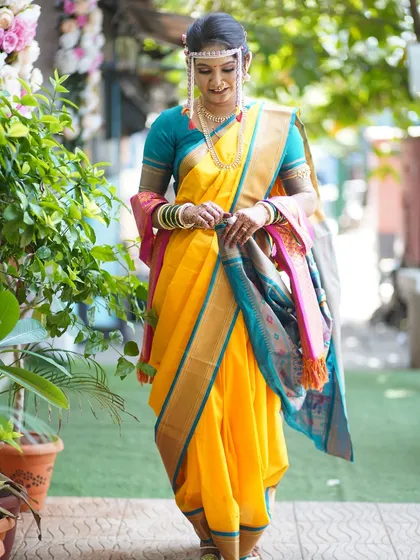 Adjusting her Nauvari saree, the bride looks elegant and poised. The makeup and hair are styled to withstand all the activities of a long wedding day.