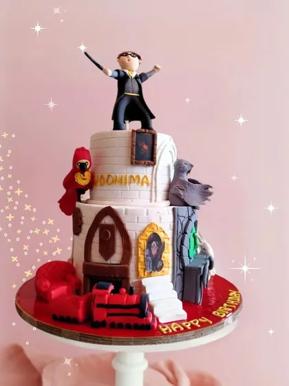 For the ultimate Harry Potter fan, this magical two-tier Hogwarts-themed cake features incredible fondant details, including a miniature Harry, Fawkes the phoenix, and the Hogwarts Express. It's a truly enchanting centerpiece for a magical birthday.