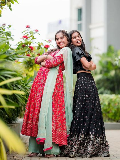 Two sisters, dressed in beautiful ethnic wear, share a fun moment during their family photoshoot.