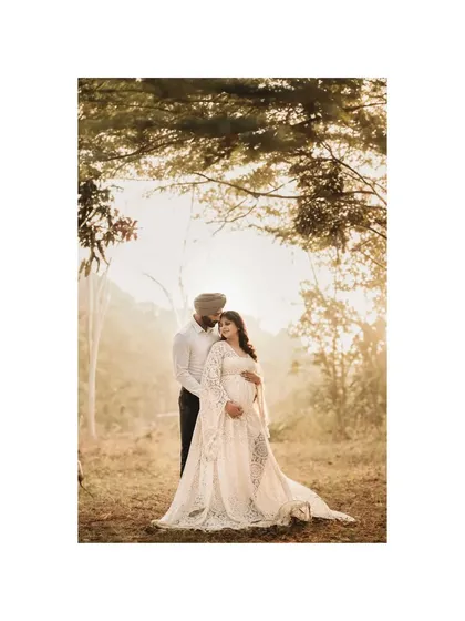 A couple stands embraced in a forest clearing, bathed in the soft glow of the setting sun. This maternity portrait captures the quiet promise and deep love between two people as they await the arrival of their child, a new chapter in their story.