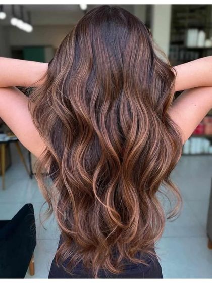 A classic chocolate brown hair color. This rich, warm shade adds depth and shine, and we styled it with soft waves to show off the dimension.