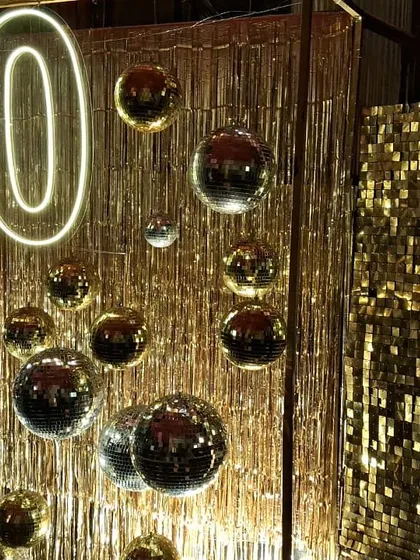 The details make the design. Here you can see the interplay of the neon '50' sign with the reflective disco balls and the shimmering gold fringe, creating a dynamic and festive environment.