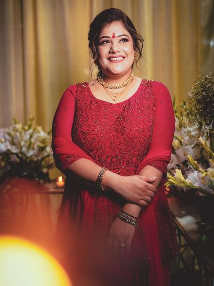 Ishita's engagement look in a beautiful red gown. The makeup is soft and romantic, with a simple bindi and gold jewellery.