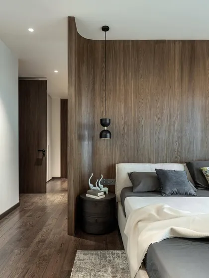Good design solves problems with elegance. In this guest bedroom, I introduced a curved wooden partition to cleverly conceal the wardrobe area while maximizing space and preserving the beautiful window views.