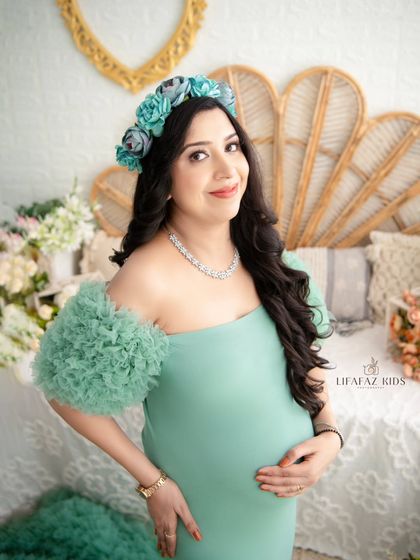 A close-up look at our soft mint green gown. The delicate ruffled sleeves and fitted bodice are incredibly flattering, and the color is fresh and serene. It's styled here with a matching floral headband.