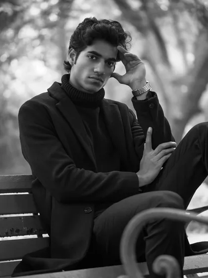 A classic black and white portrait of a male model on a park bench. This moody, cinematic style is ideal for lookbooks and editorials that aim to tell a deeper story.