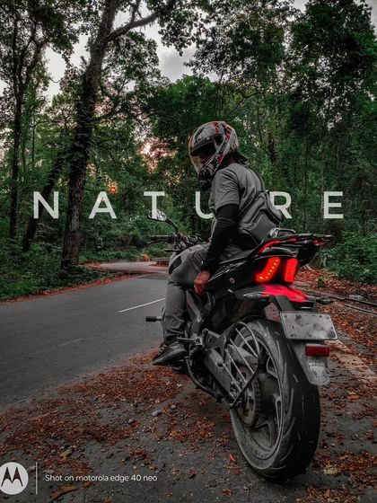 A rider and his Dominar parked on a quiet road, surrounded by the tranquility of a forest. These nature rides are a perfect way to unwind.