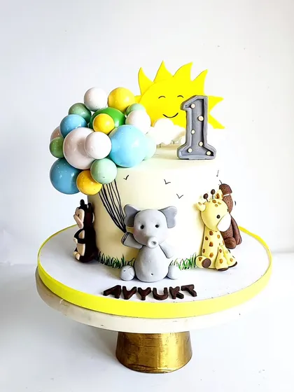 Sunshine and animals were the themes for little Avyukt's first birthday. This cake combines his favorite things, including a cheerful sun, colorful balloons, and cute jungle animals.