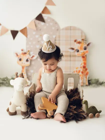 A baby boy sits in his giraffe-themed setup, playing with a wooden star toy. These prop-based shoots allow for lots of cute, interactive moments.