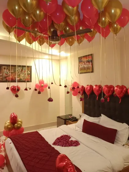 I can turn any hotel room into a romantic haven. This classic "I love you" decor uses a red and gold theme with dozens of helium balloons on the ceiling, rose petals on the bed and floor, and heart-shaped foil balloons to complete the look.