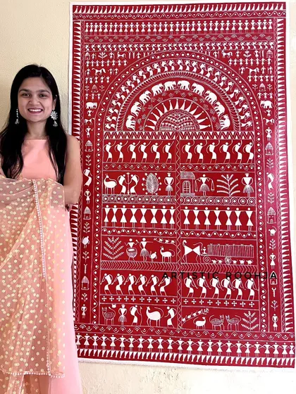 Posing with a large, intricate Warli canvas painting. My course teaches how to compose and execute such detailed traditional artworks.