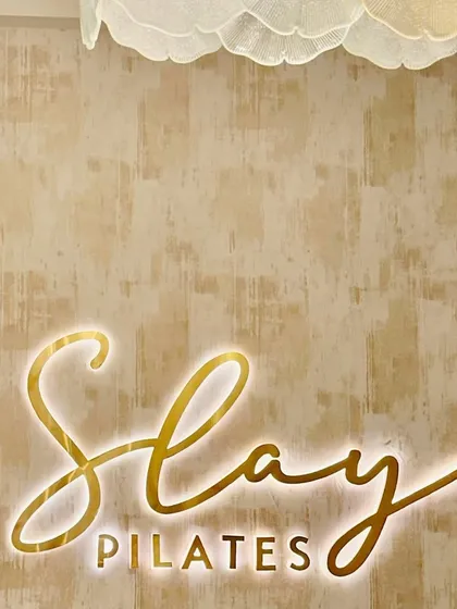 The magic happens here. A close-up of our signature illuminated "Slay Pilates" sign at our GK1 studio, setting the vibe for every session.