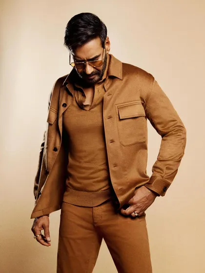 This shot shows the layered textures of the brown knit, jacket, and trousers, creating a rich and luxurious look.