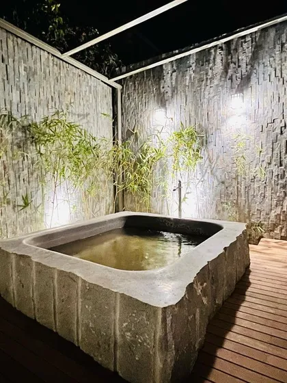 We specialize in creating serene, Zen-inspired spaces. This custom-built Japanese stone bath, set against textured stone walls and bamboo, provides a private, tranquil retreat. We manage all aspects, from sourcing the natural stone to the plumbing and lighting installation.