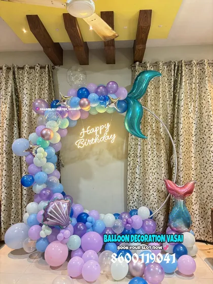 Dive into a magical underwater world with our mermaid theme. This setup features a ring backdrop decorated with pastel balloons, a shimmering mermaid tail, and a neon sign, perfect for a whimsical birthday party.