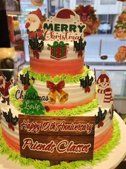 A festive cake that combines a 10th-anniversary celebration with the joy of Christmas. This three-tier cake is decorated with holiday elements like Santa, a snowman, and jingle bells.