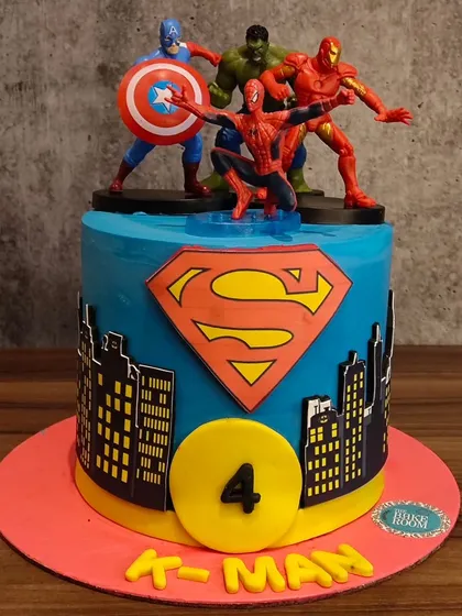 A superhero-themed cake for a 4th birthday. This cake brings together heroes like Captain America, Hulk, Iron Man, and Spider-Man, set against a city skyline with the Superman logo.