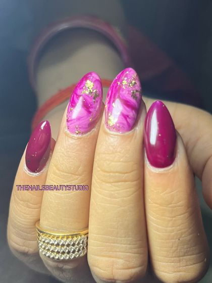 A vibrant pink and magenta set featuring a marble effect on two nails, accented with delicate gold foil.
