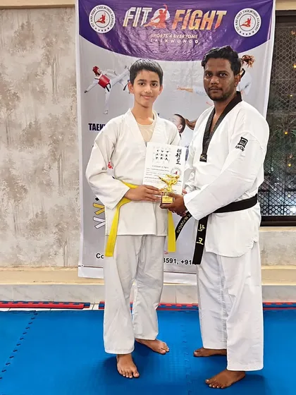 Another student is recognized for his achievement, receiving his certificate and trophy at the belt exam ceremony.