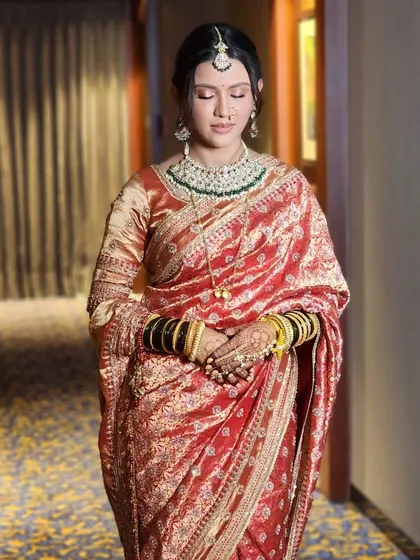 A close-up of the bride's traditional red saree, highlighting the rich fabric and the classic pairing with green jewelry and bangles.