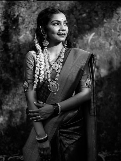 A striking black and white portrait of a bride in a traditional South Indian saree, her thoughtful expression creating a timeless and powerful image.