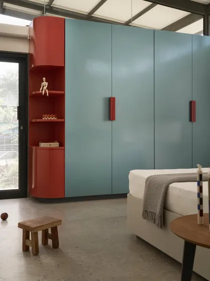 We introduced a playful burst of color in this Pavilion House bedroom with a custom-designed blue and red wardrobe. This element adds a youthful touch to the otherwise minimalist and monochrome aesthetic of the home.