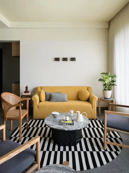 This living room features a bright yellow sofa I designed to add a touch of color and energy. Paired with neutral armchairs and a striking black and white rug, it creates a balanced and cheerful space.