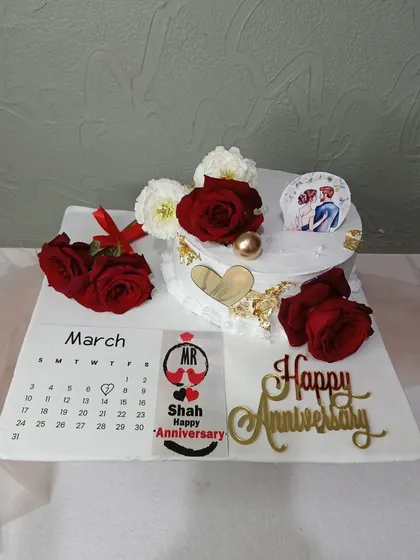 A full view of the calendar-themed anniversary cake, marking the special day with red roses.