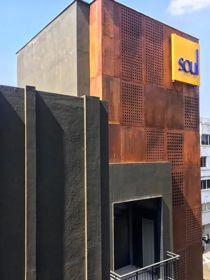 A detail shot of the Koramangala commercial property, highlighting the contrast between the textured dark grey finish and the weathered steel panels.
