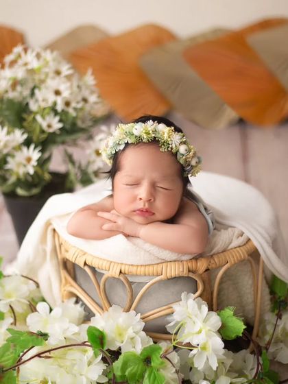 This little one is resting peacefully, framed by a cascade of white flowers and greenery. The mix of textures creates a visually stunning portrait.