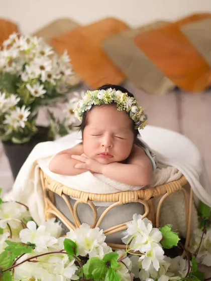 This little one is resting peacefully, framed by a cascade of white flowers and greenery. The mix of textures creates a visually stunning portrait.