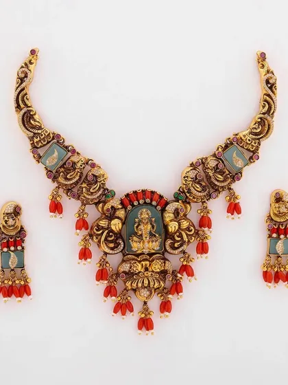 This is a truly regal piece from my collection. A handcrafted bridal necklace set featuring a depiction of Goddess Lakshmi, surrounded by intricate metalwork and vibrant red coral beads. This is the kind of heirloom-quality jewellery that is passed down through generations.