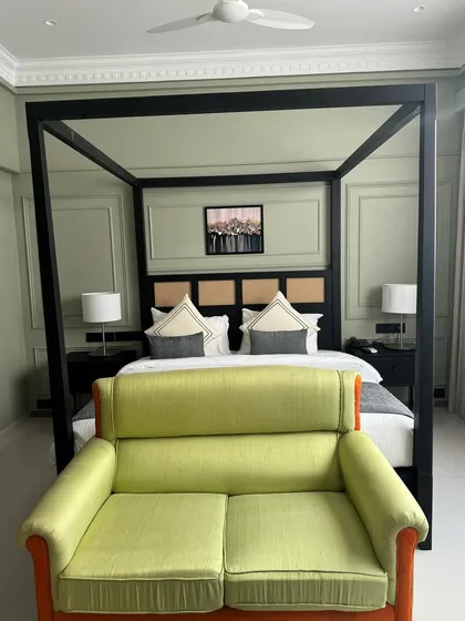 Another room from the hotel project, featuring the modern canopy bed and a bright green loveseat.