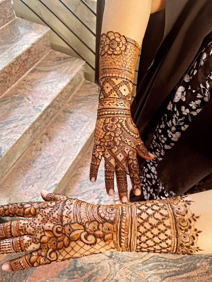 A stylish pose on the stairs showing off this traditional Indian henna design. The pattern includes detailed finger work and wrist cuffs.