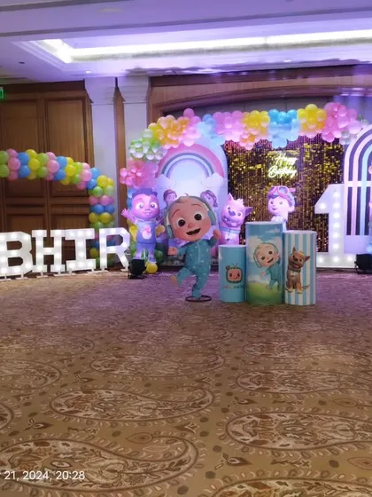 The main stage for the Cocomelon party, featuring character cut-outs, marquee letters, and multiple rainbow-themed balloon arches.