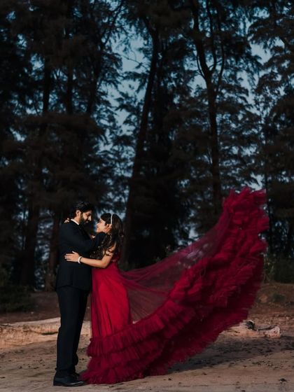 A romantic shot of a couple in the woods at night. The woman's flowing red gown creates a dramatic and enchanting effect.