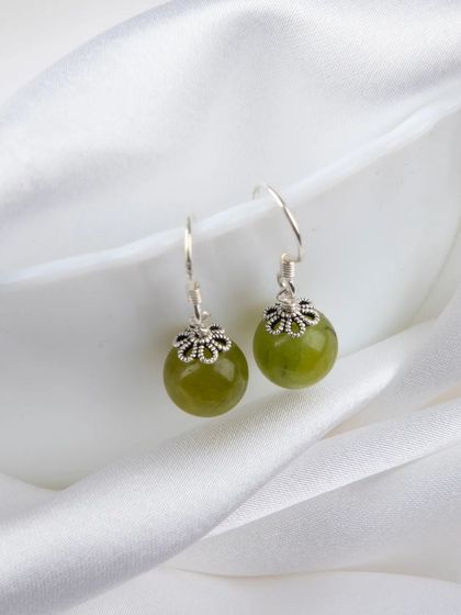 A pair of simple yet elegant drop earrings with green jade-like stones and silver floral caps.
