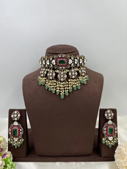 A full display of another masterpiece, this heavy bridal choker features a central emerald and ruby motif surrounded by heart-shaped polki stones. The set comes with matching jhumka-style earrings.