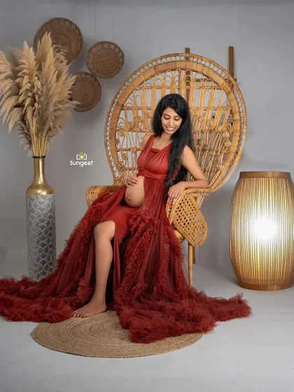 A relaxed and happy solo portrait in our boho peacock chair, showcasing the beautiful red ruffled gown.