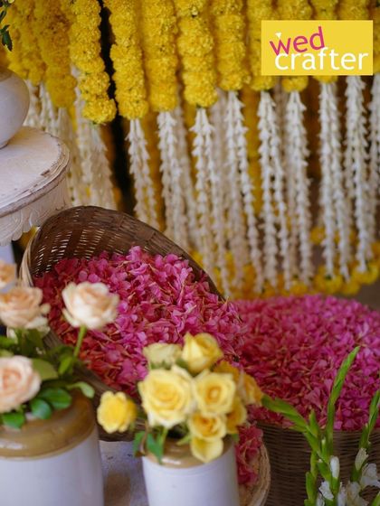 A close-up of the flower arrangements for the Haldi, with baskets of petals and vases of fresh roses ready for the celebration.