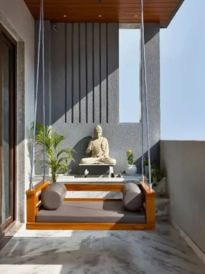 For this balcony, we created a serene meditation corner featuring a simple wooden swing. The space is anchored by a Buddha statue set against a textured grey wall, creating a peaceful and minimalist retreat.