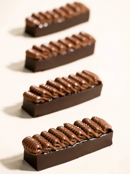 A minimalist shot of piped chocolate bars for Morde. The clean composition and lighting focus entirely on the texture and form, showcasing the chocolate itself as the hero.