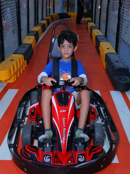 This young driver is focused and ready to race on our indoor go-kart track. The safety harness and sturdy kart ensure parents can relax while the kids have a blast.