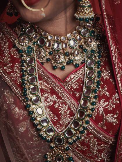 Another perspective on the bride's stunning jewelry set. This detailed photograph captures the way the heavy necklaces lay, showing the beautiful combination of polki and green beads that complete her bridal look.