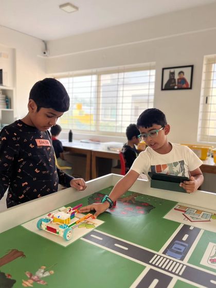 Problem-solving in action. Two students collaborate to test their robot on one of our interactive learning mats, figuring out the code needed to navigate the city-themed challenge.