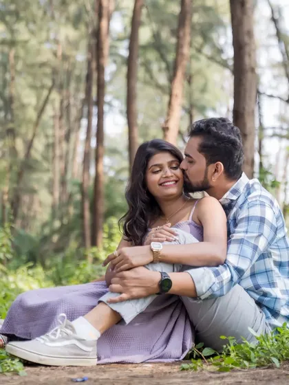A tender kiss on the cheek captures the couple's affection during their woodland pre-wedding session. The natural surroundings provide a perfect, tranquil backdrop.