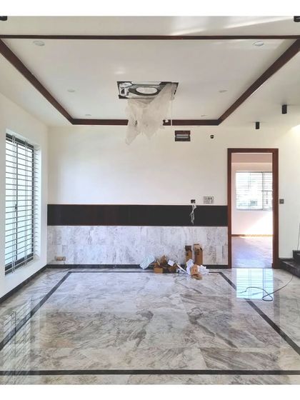 A living room during the final stages of finishing, showing the beautiful Italian marble floor with a dark stone border.