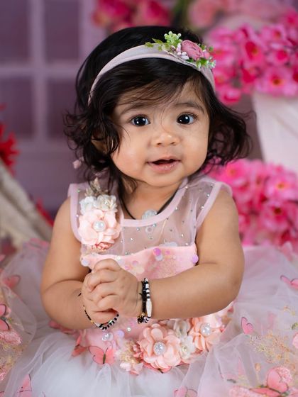 A sweet close-up portrait of a toddler girl in a beautiful pink dress, capturing her innocent and curious expression.