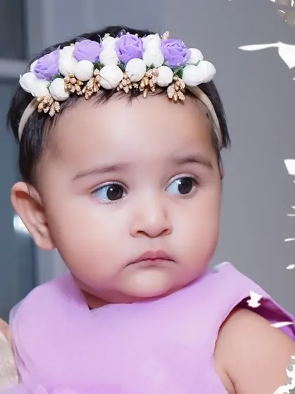 A beautiful close-up portrait of a baby girl wearing a delicate floral headband, showcasing the sharp detail we capture in our photos.